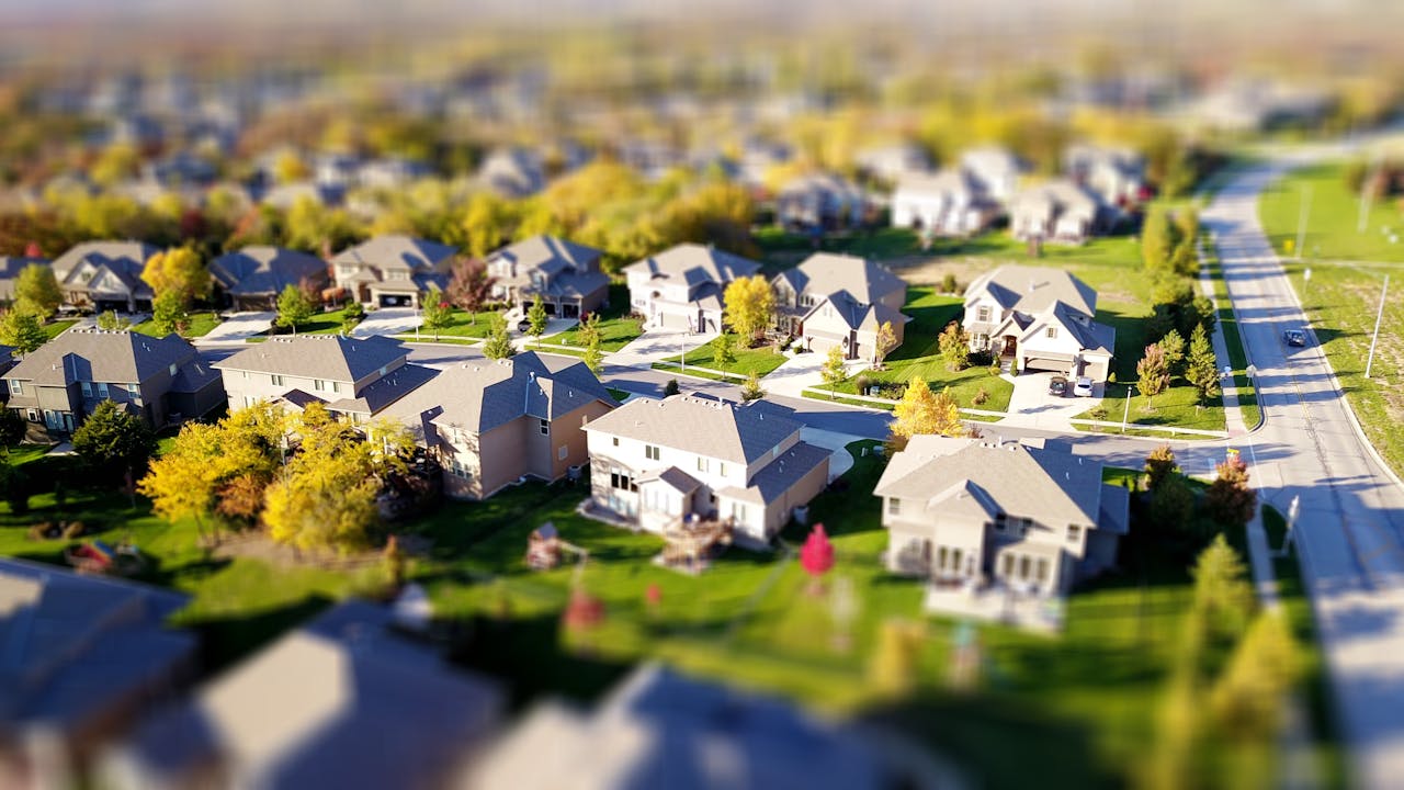 portfolio-01 Tilt-shift aerial photo of a suburban neighborhood with green lawns and roads.